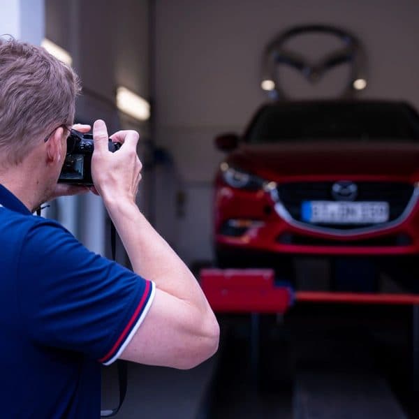 Gutachter / Kfz-Sachverständiger fotografiert ein Auto