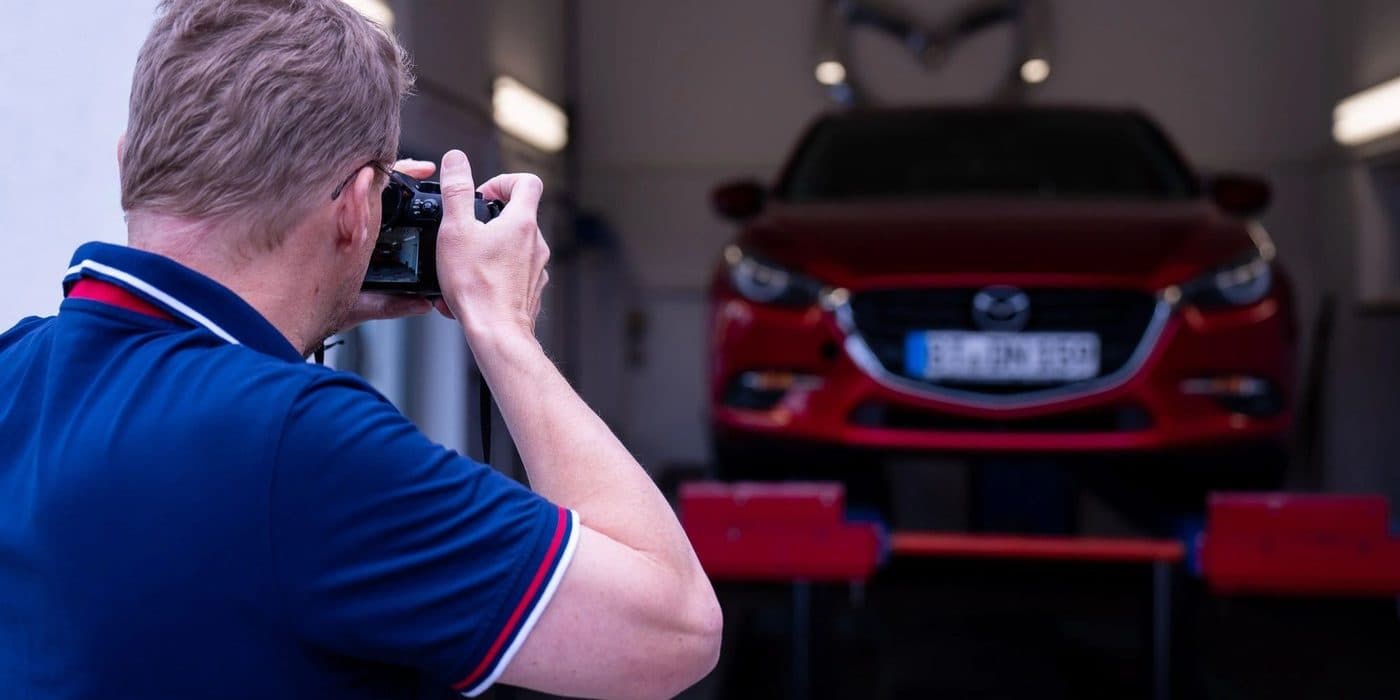 Gutachter / Kfz-Sachverständiger fotografiert ein Auto